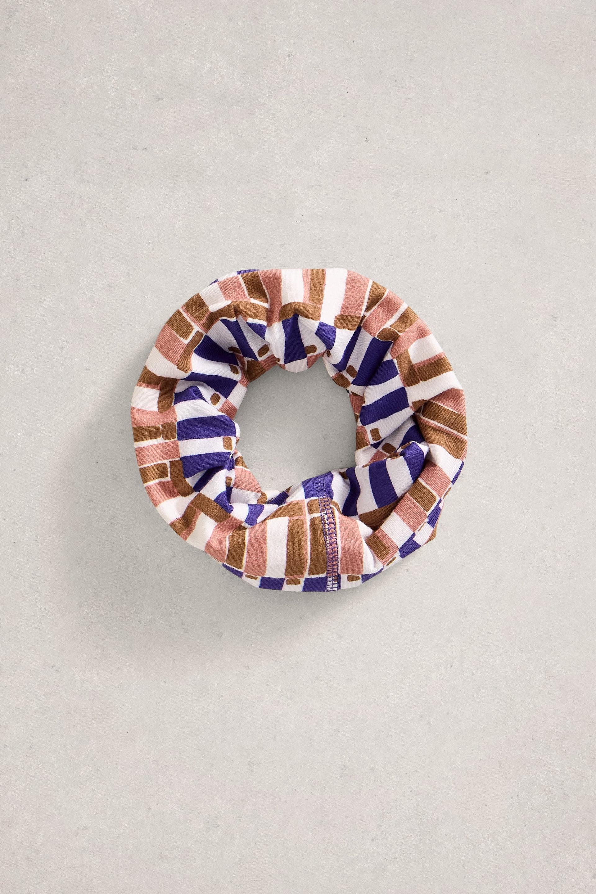 A patterned scrunchie with geometric blocks of purple, pink, and white fabric.