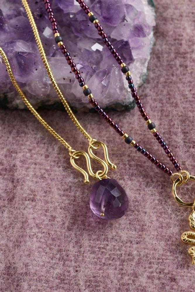 Two gold-plated necklaces, one with a faceted amethyst gemstone and one with a small gold snake charm