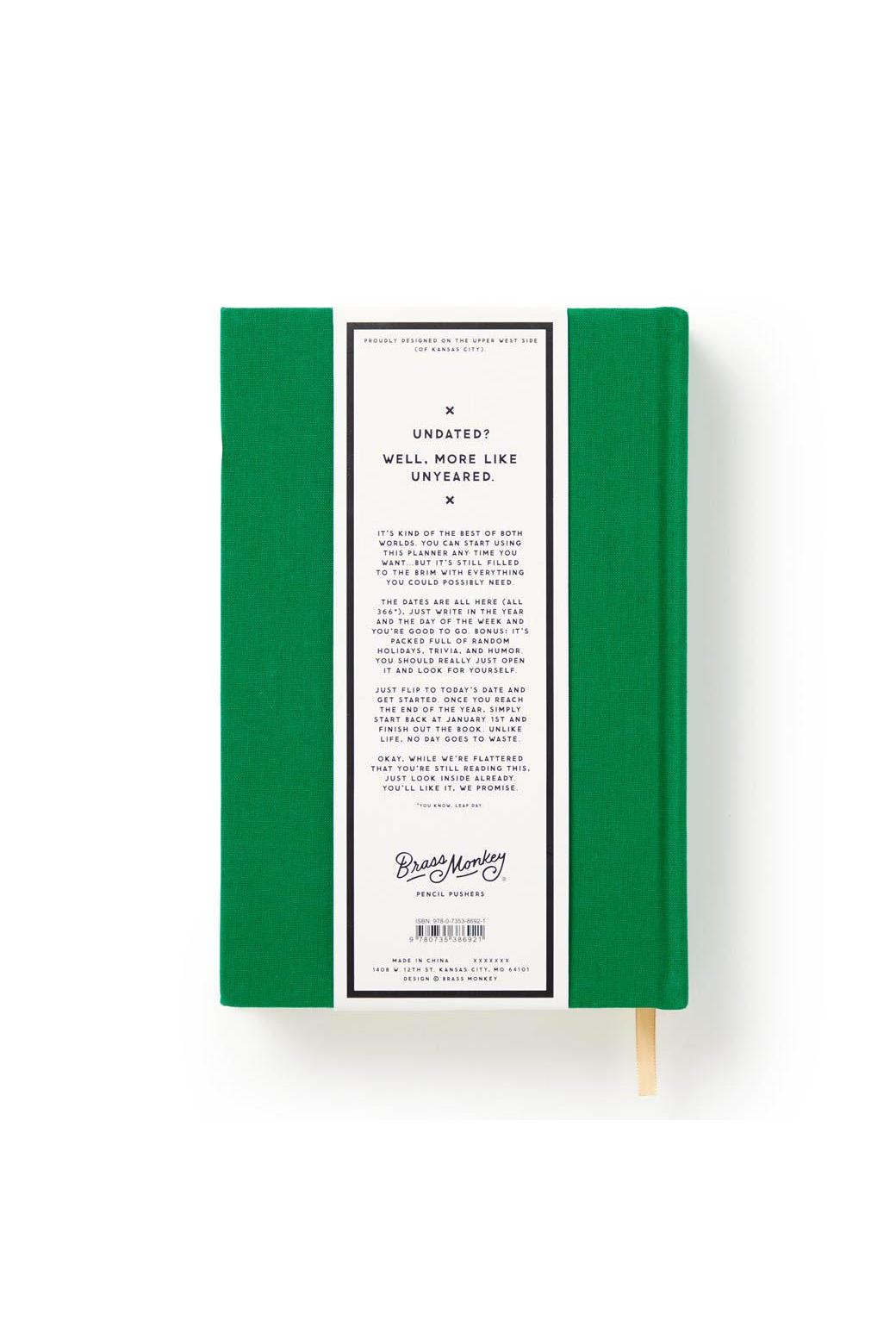 Green undated planner by Brass Monkey with a descriptive paper band featuring white text on a black background.