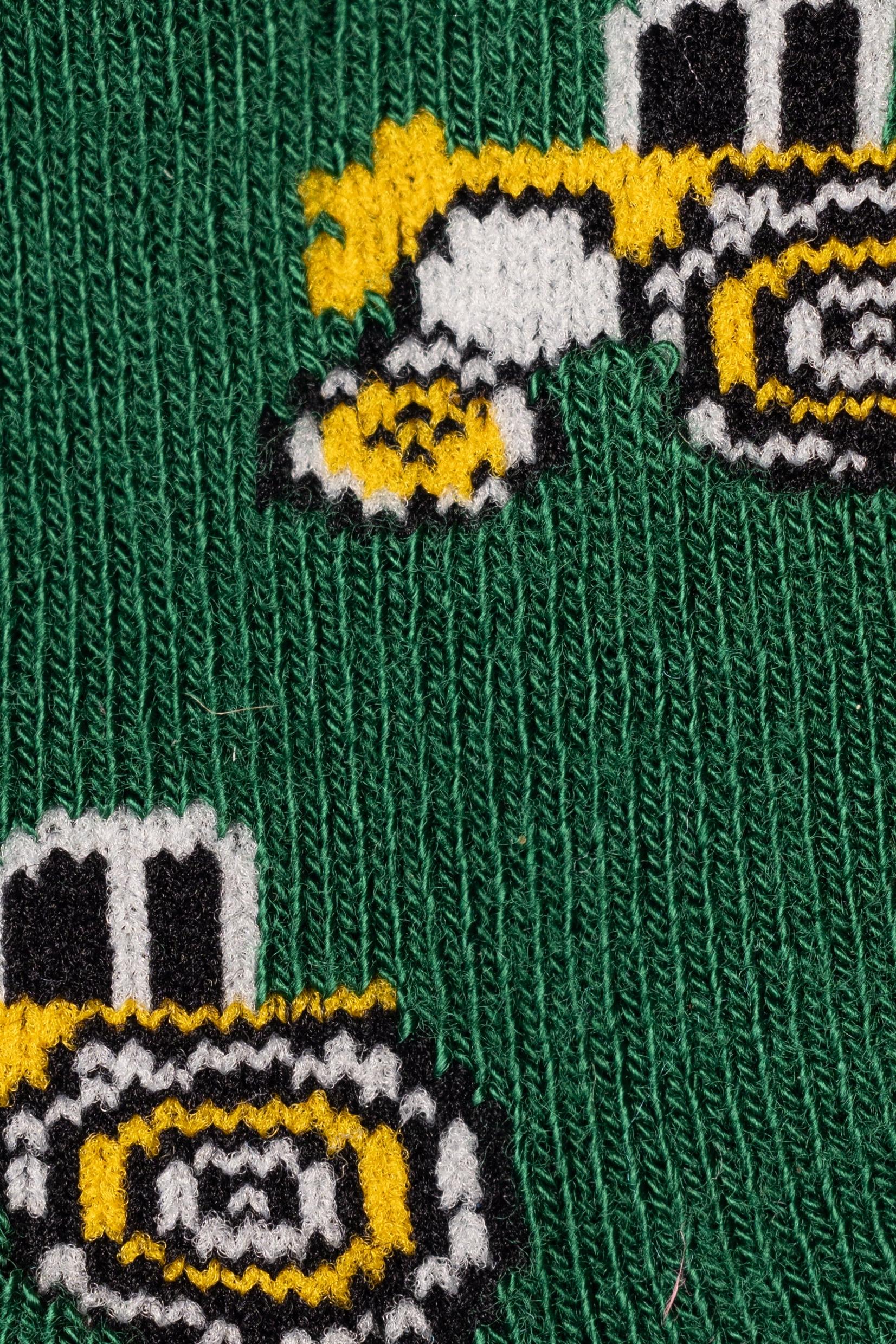 Close-up view of green fabric featuring a repeating pattern of yellow and black construction trucks.