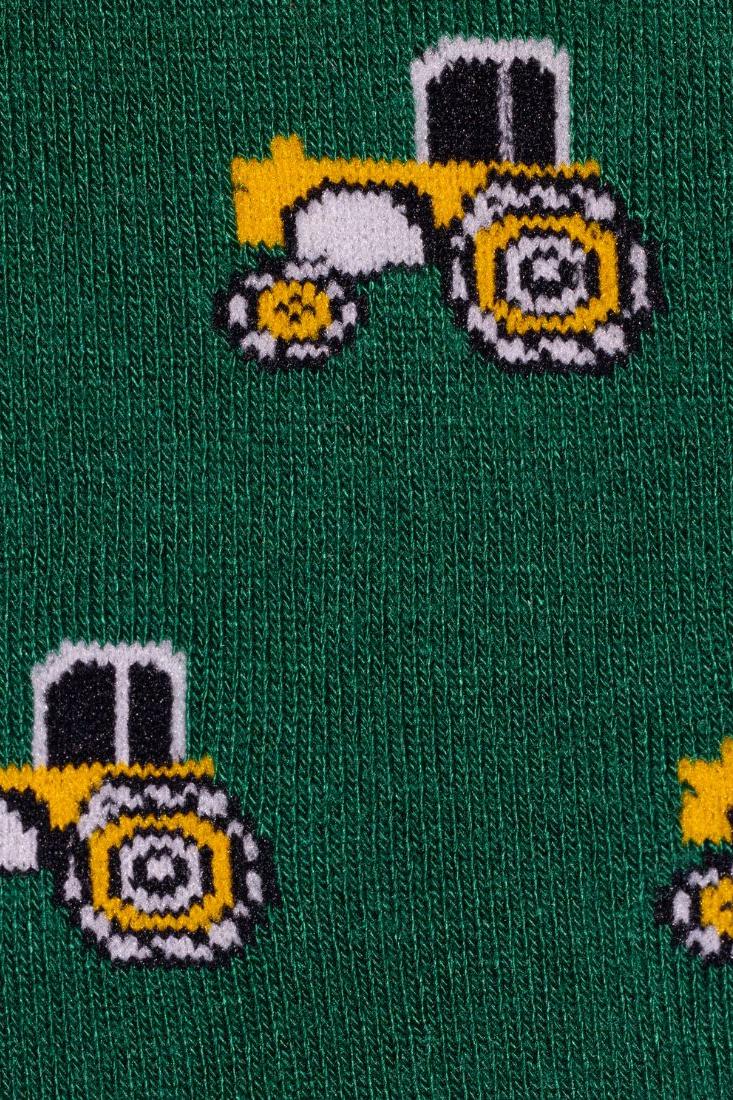 A close-up view of dark green fabric featuring a repeating pattern of yellow and white tractors.