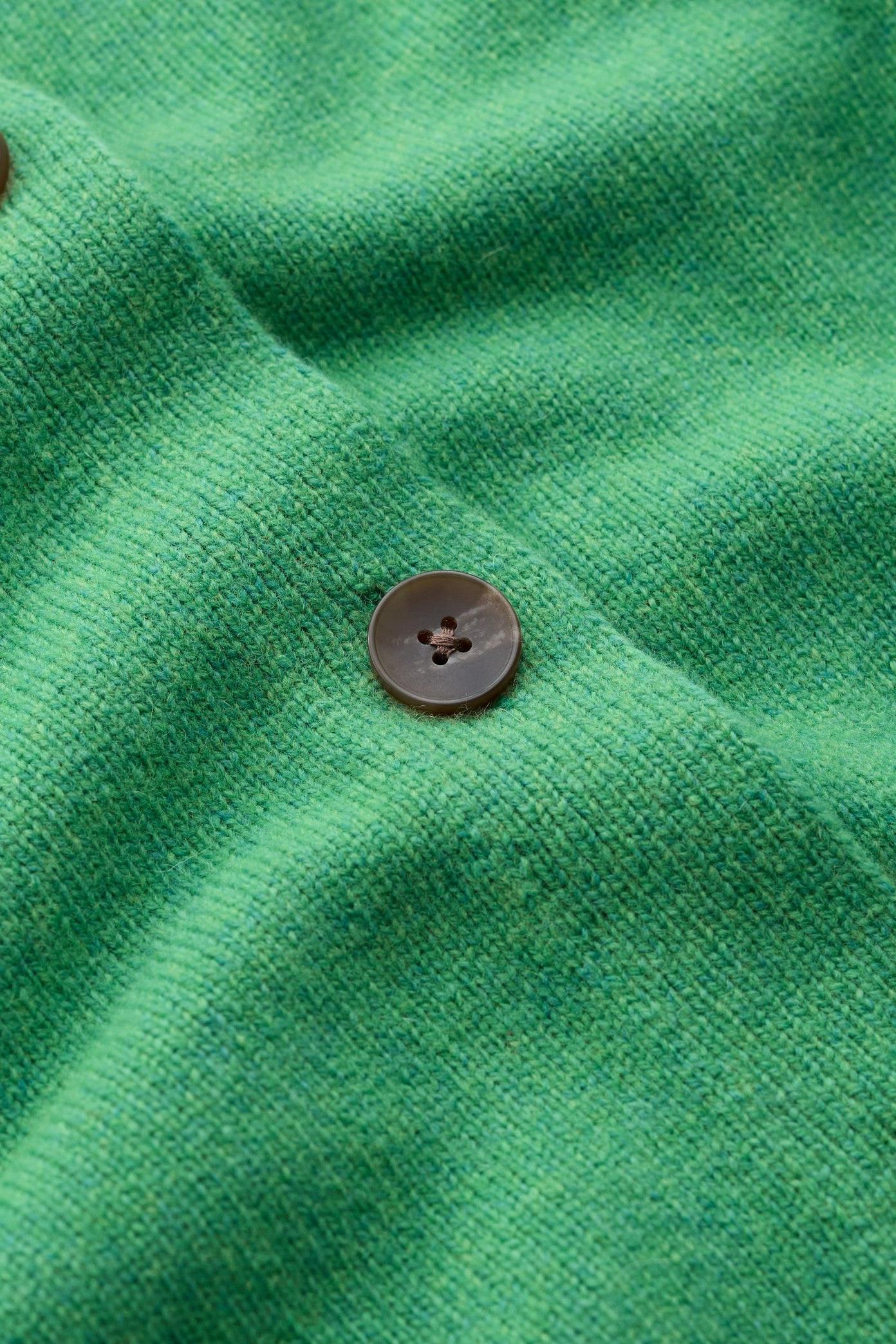 Close-up of a green knit cardigan or sweater fabric with visible brown buttons.