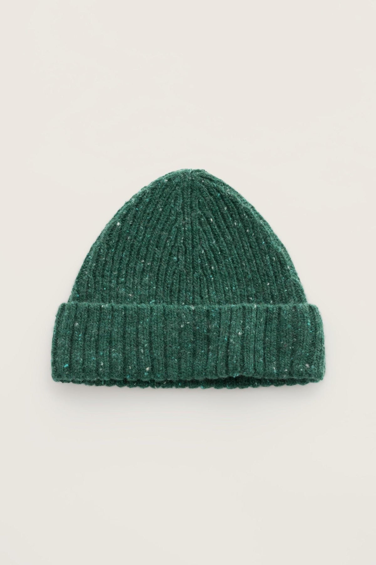 A green ribbed knit hat made from merino wool against a neutral background.