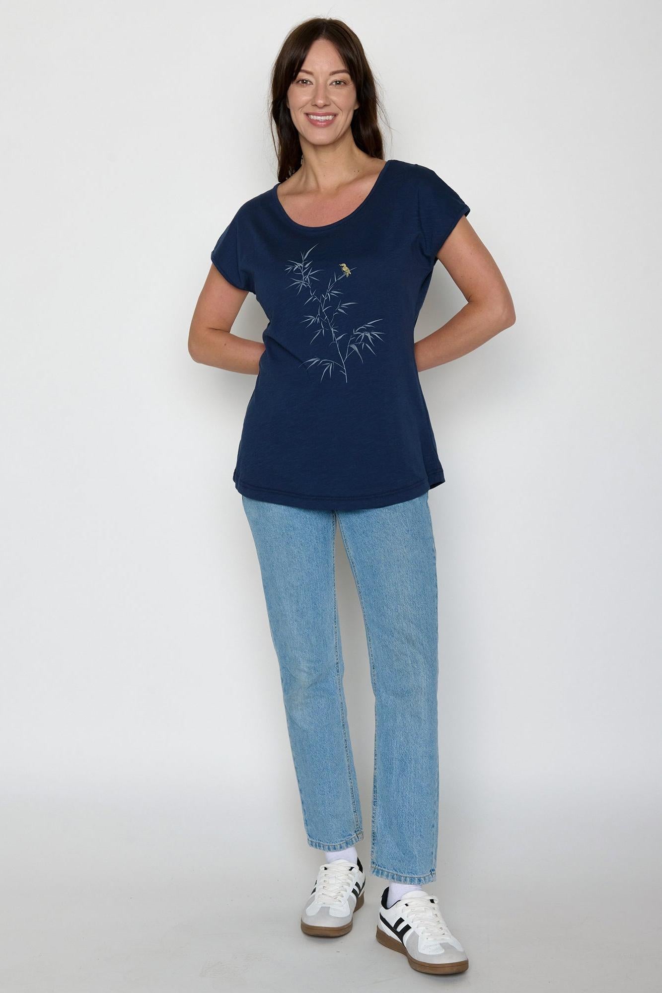 Woman wearing a navy blue t-shirt with a graphic design and blue jeans on a white background