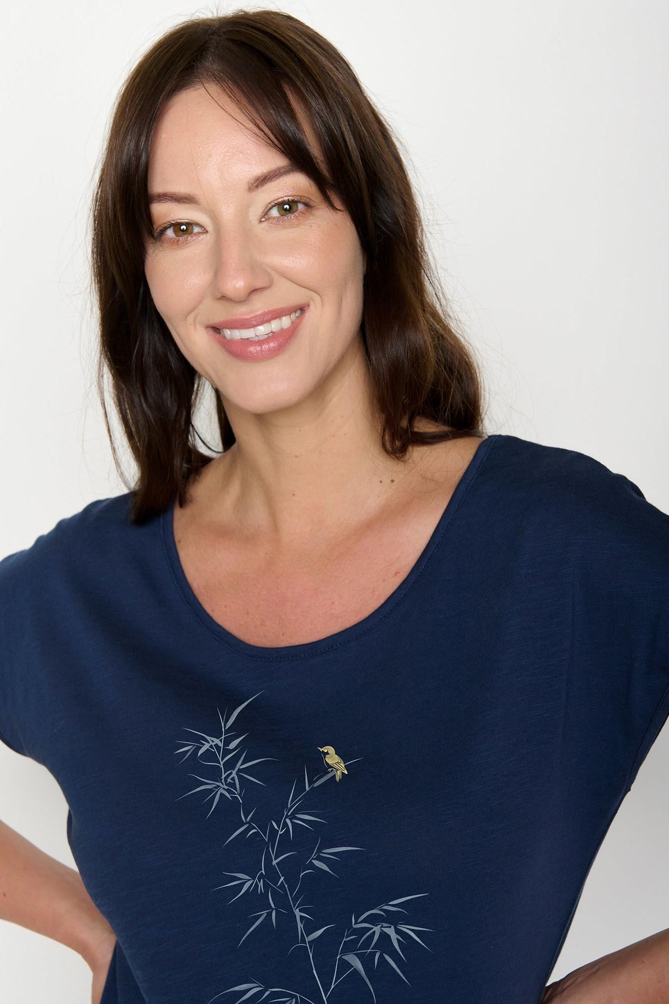 Woman wearing a navy blue organic cotton t-shirt with bamboo design on a white background