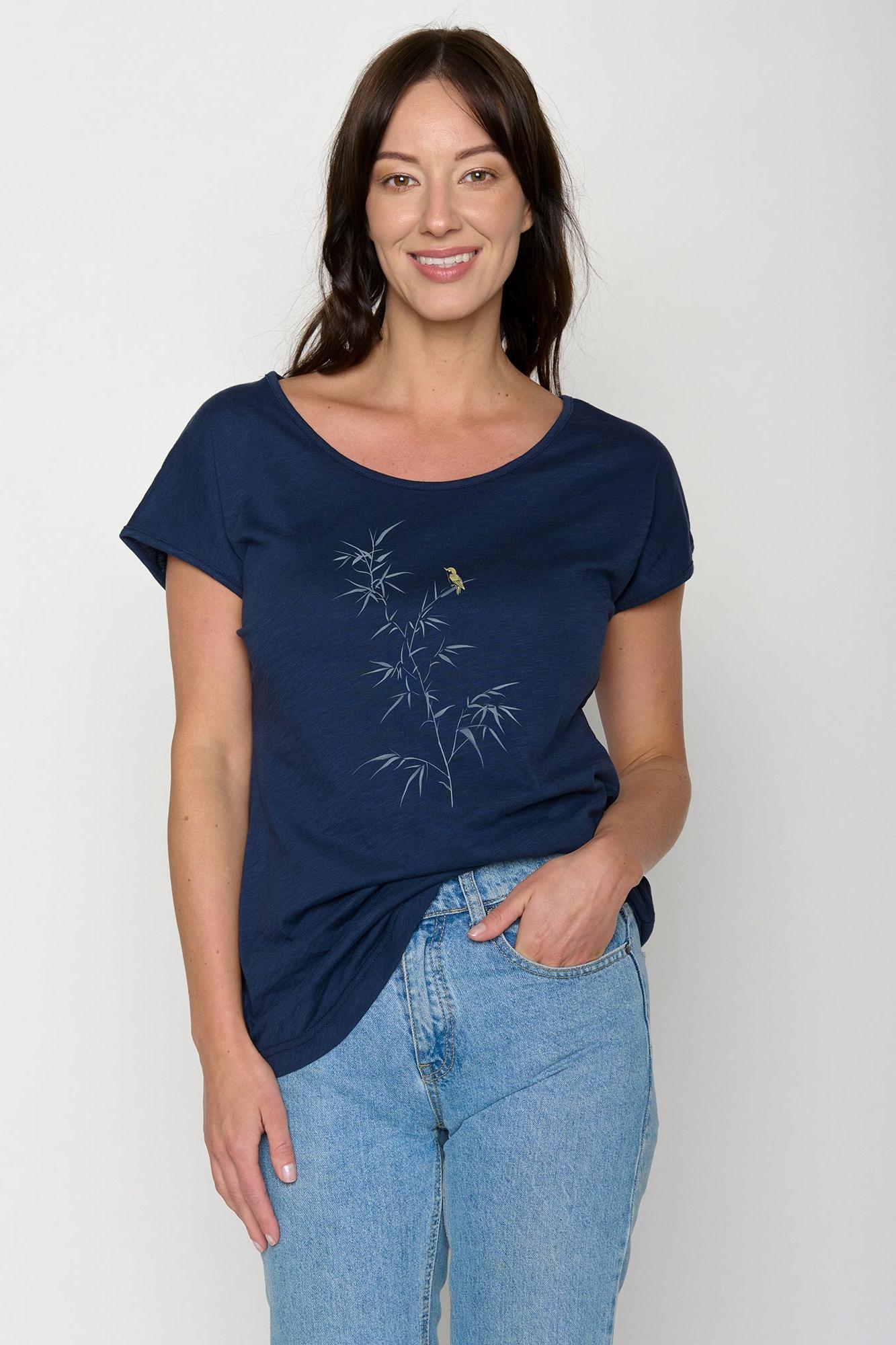 Woman wearing a navy blue t-shirt with a bamboo design and light blue jeans on a white background