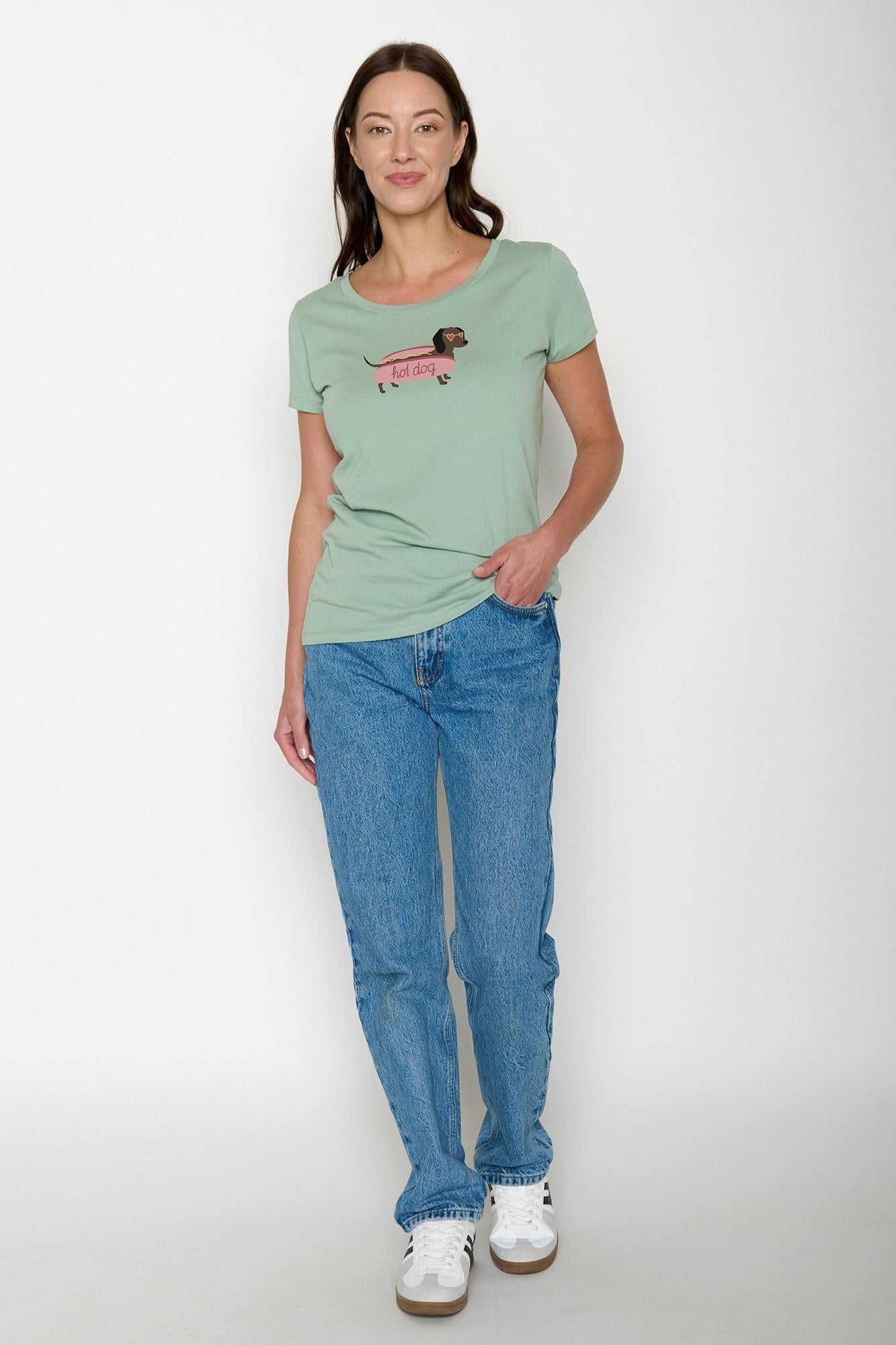 Woman wearing a green t-shirt with a graphic design and blue jeans on a white background