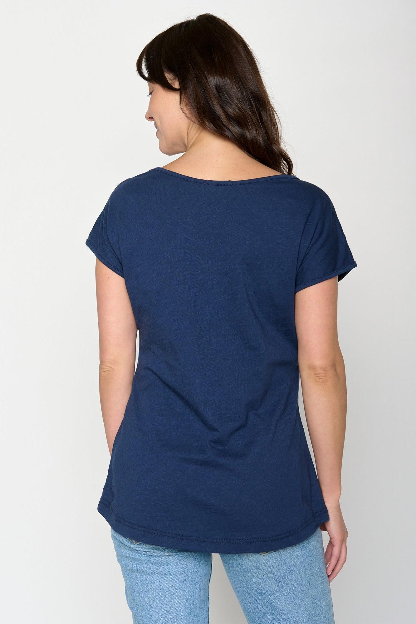 Woman wearing a navy blue organic cotton t-shirt and light blue jeans on a white background