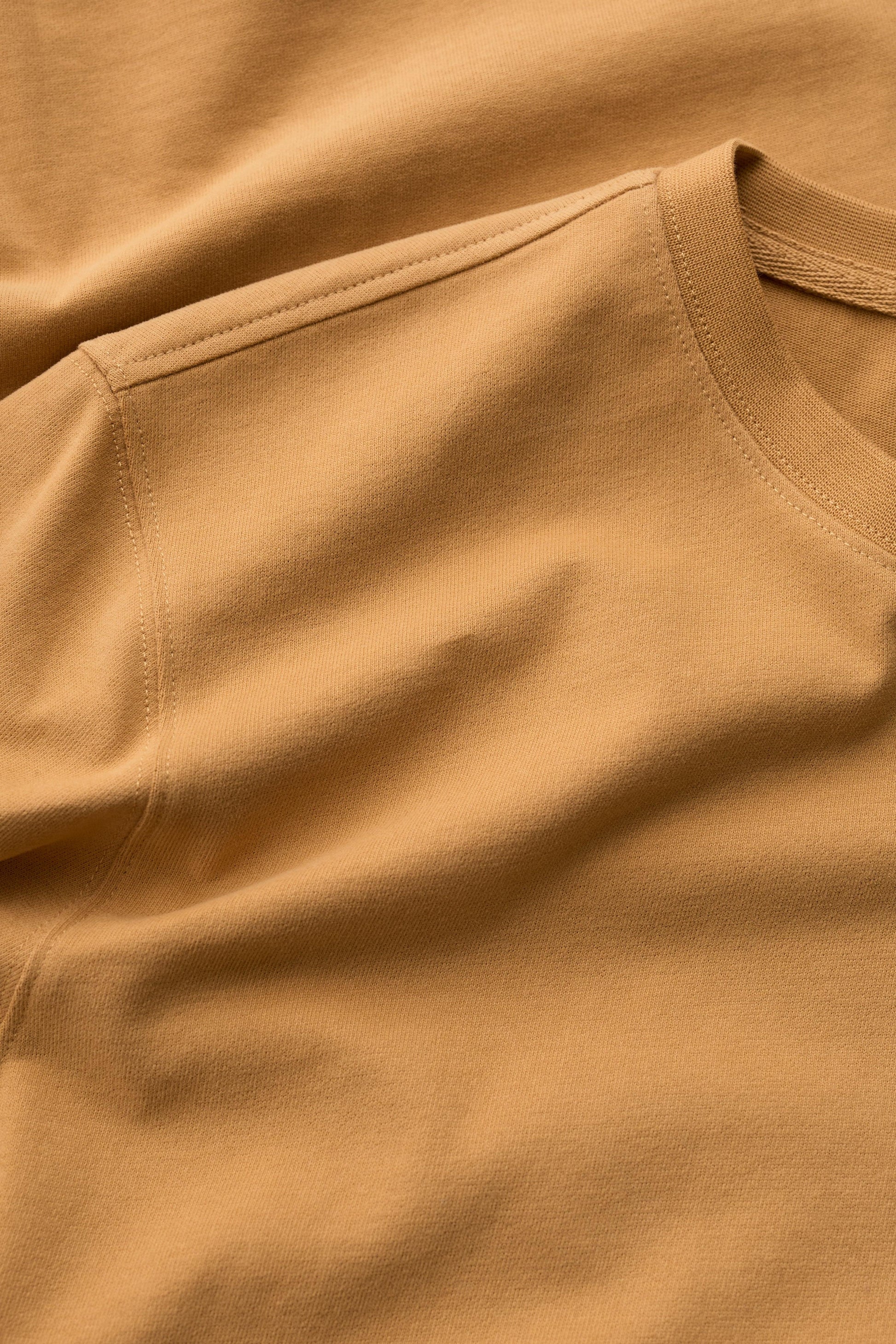 Close-up of a yellow organic cotton mens t-shirt showing the crew neck collar and soft fabric texture.
