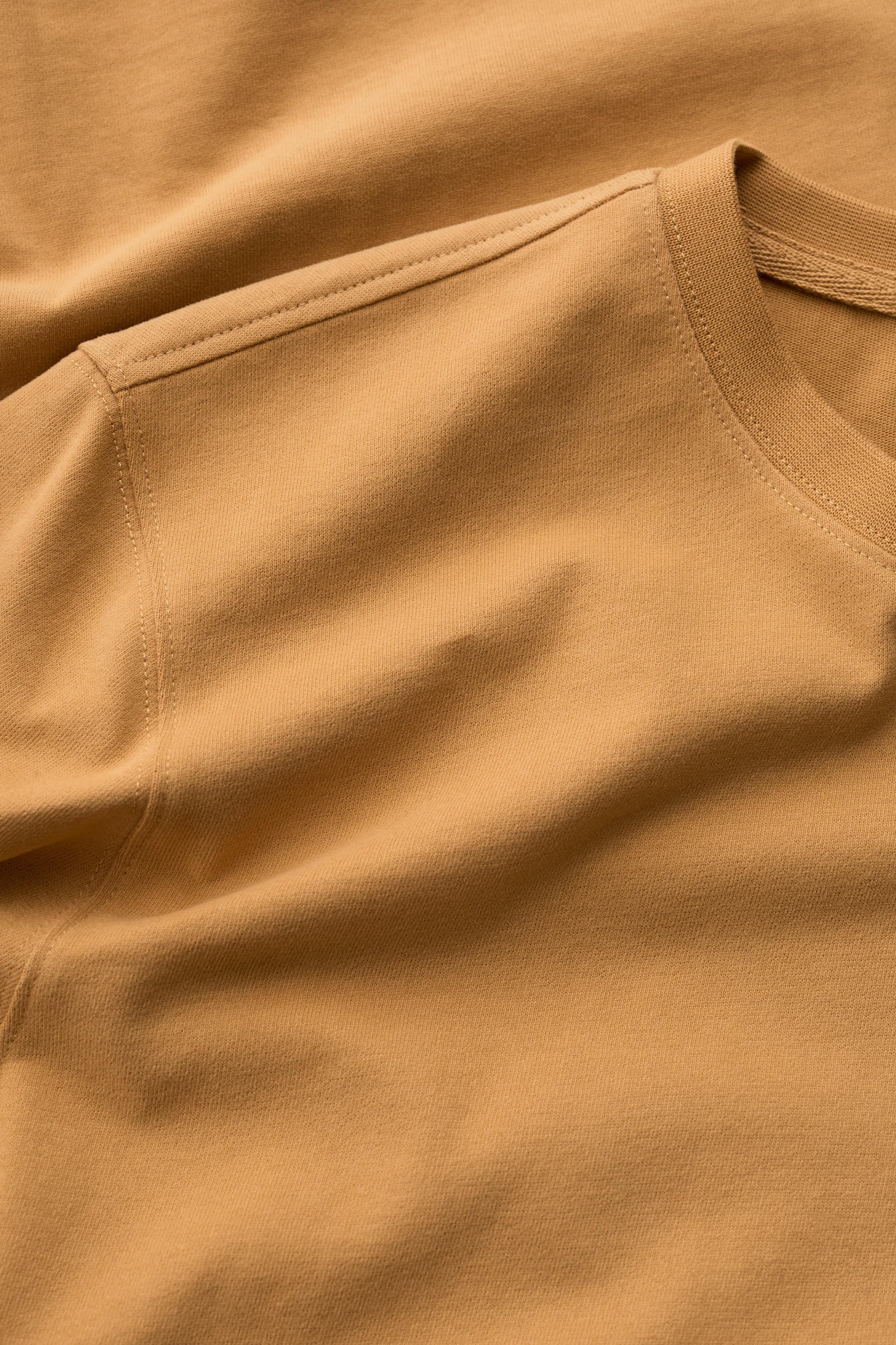 Close-up of a yellow organic cotton mens t-shirt showing the crew neck collar and soft fabric texture.