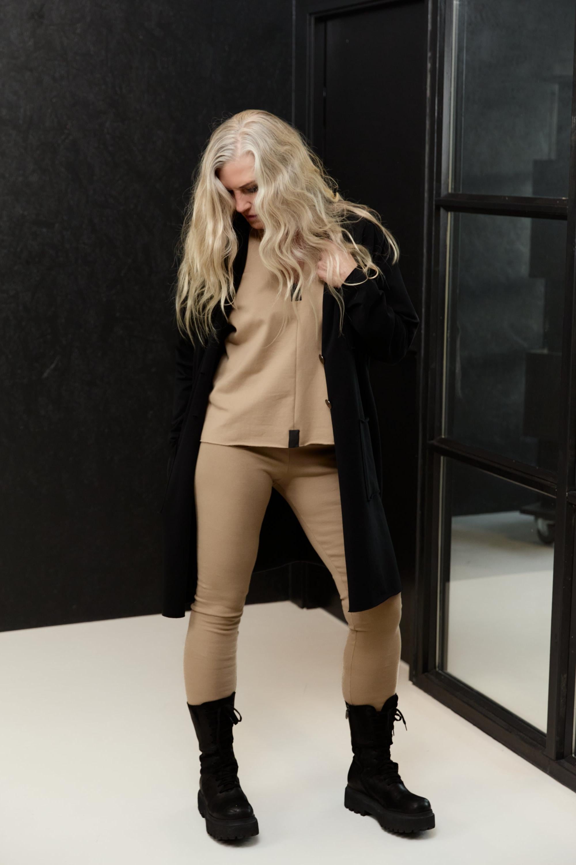 Woman wearing a black blazer and organic cotton beige top and leggings.