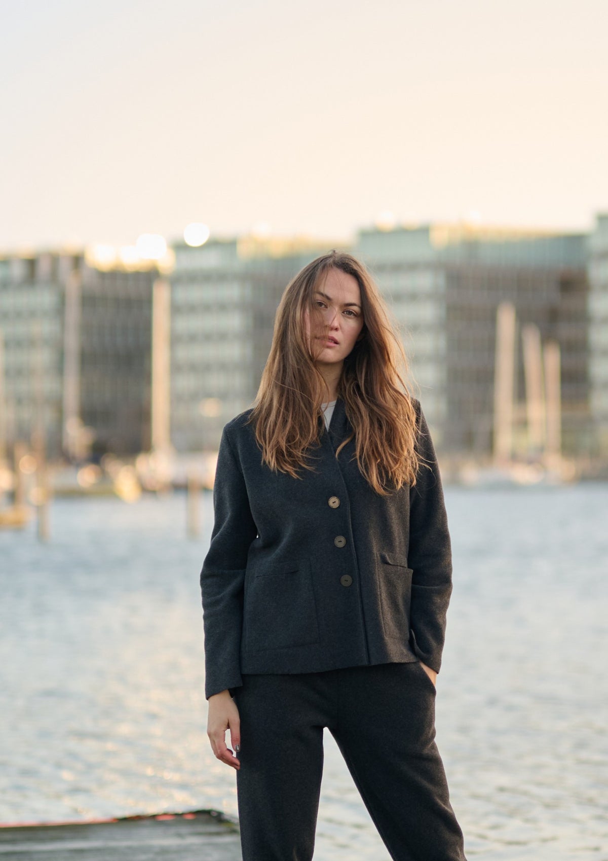 Woman standing on a pier wearing a black fleece cardigan with matching pants at sunset