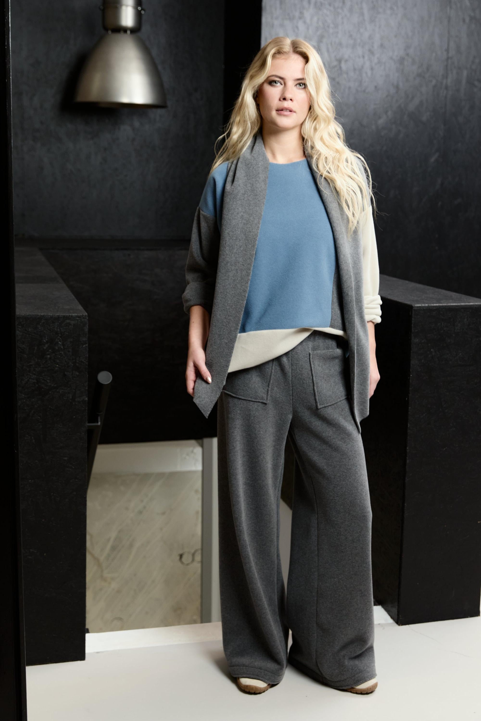 Blonde woman wearing Henriette Steffensen blue and grey fleece outfit in a modern minimalist space