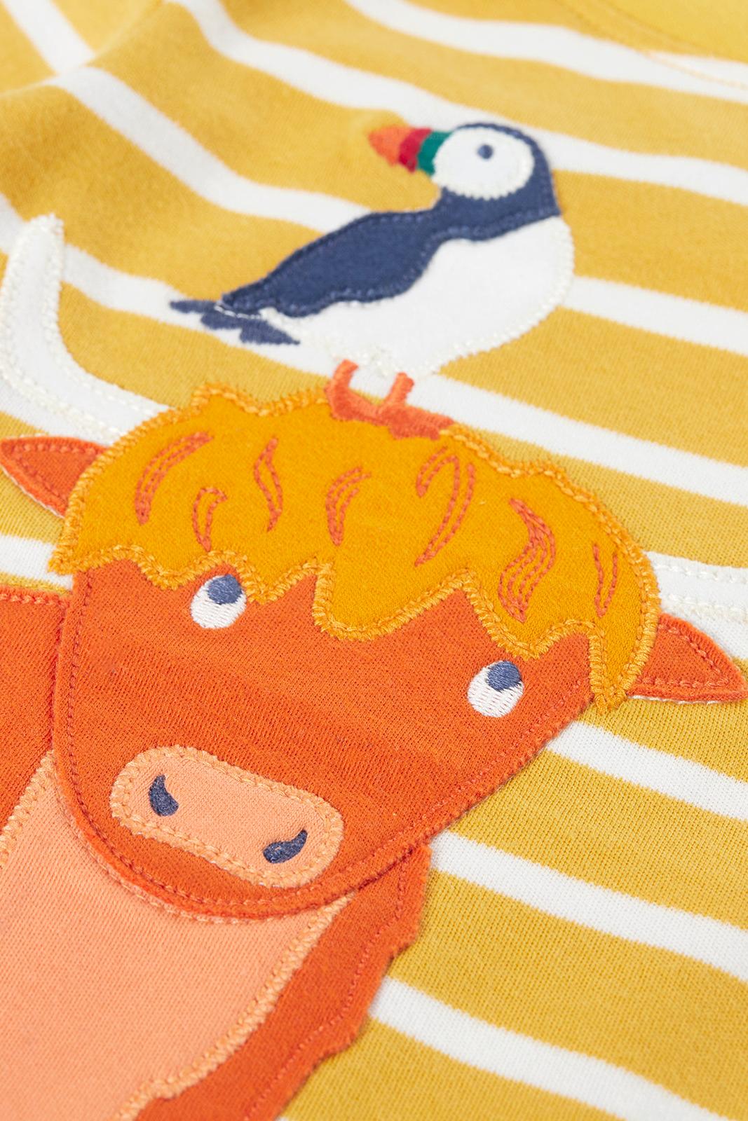 Close-up of a Frugi yellow striped organic cotton top featuring a Highland cow and puffin applique.