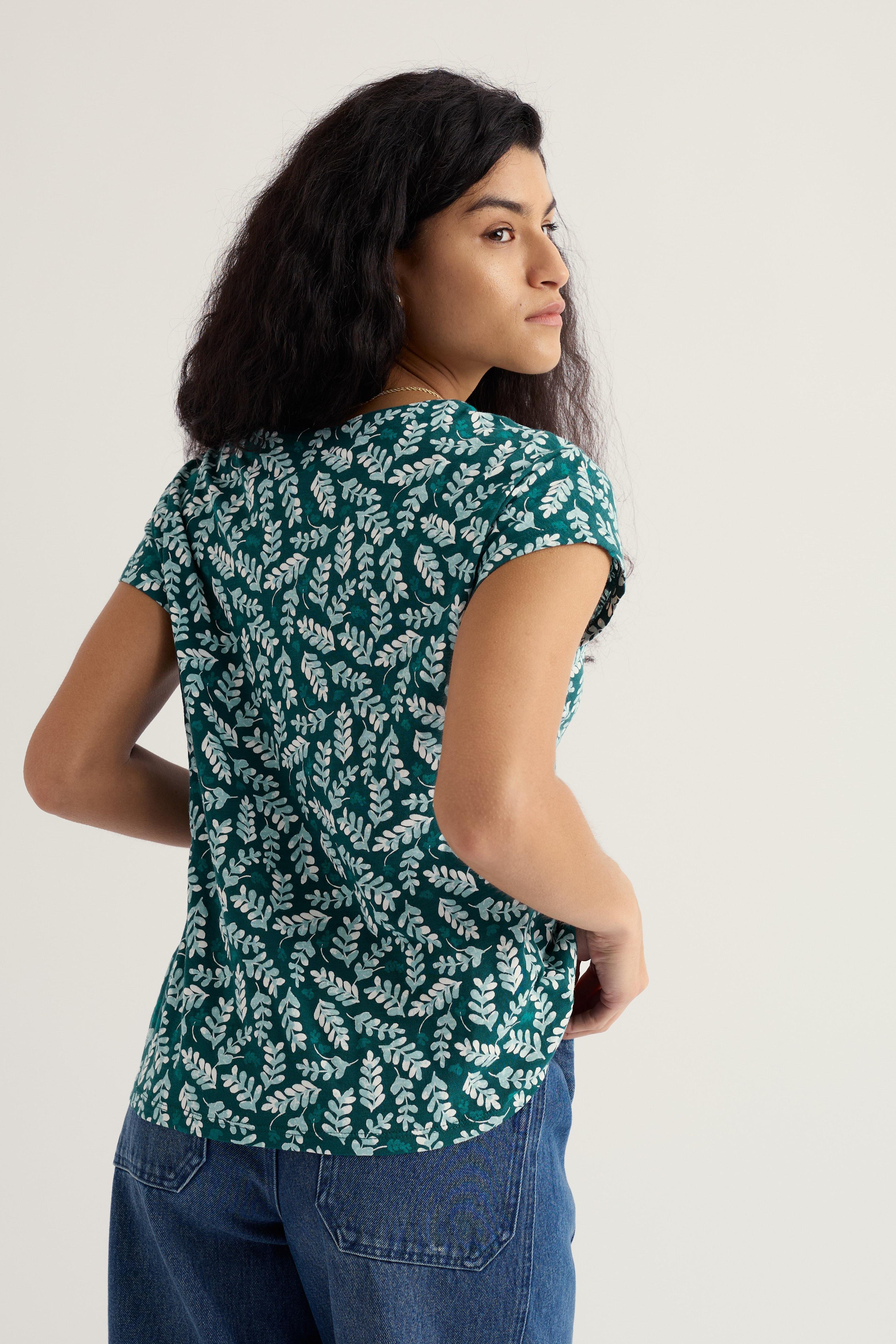 Woman wearing a green leaf-patterned shirt against a white background
