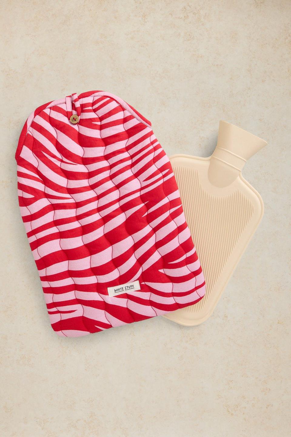 A white hot water bottle and a cotton quilted cover in a fun print.