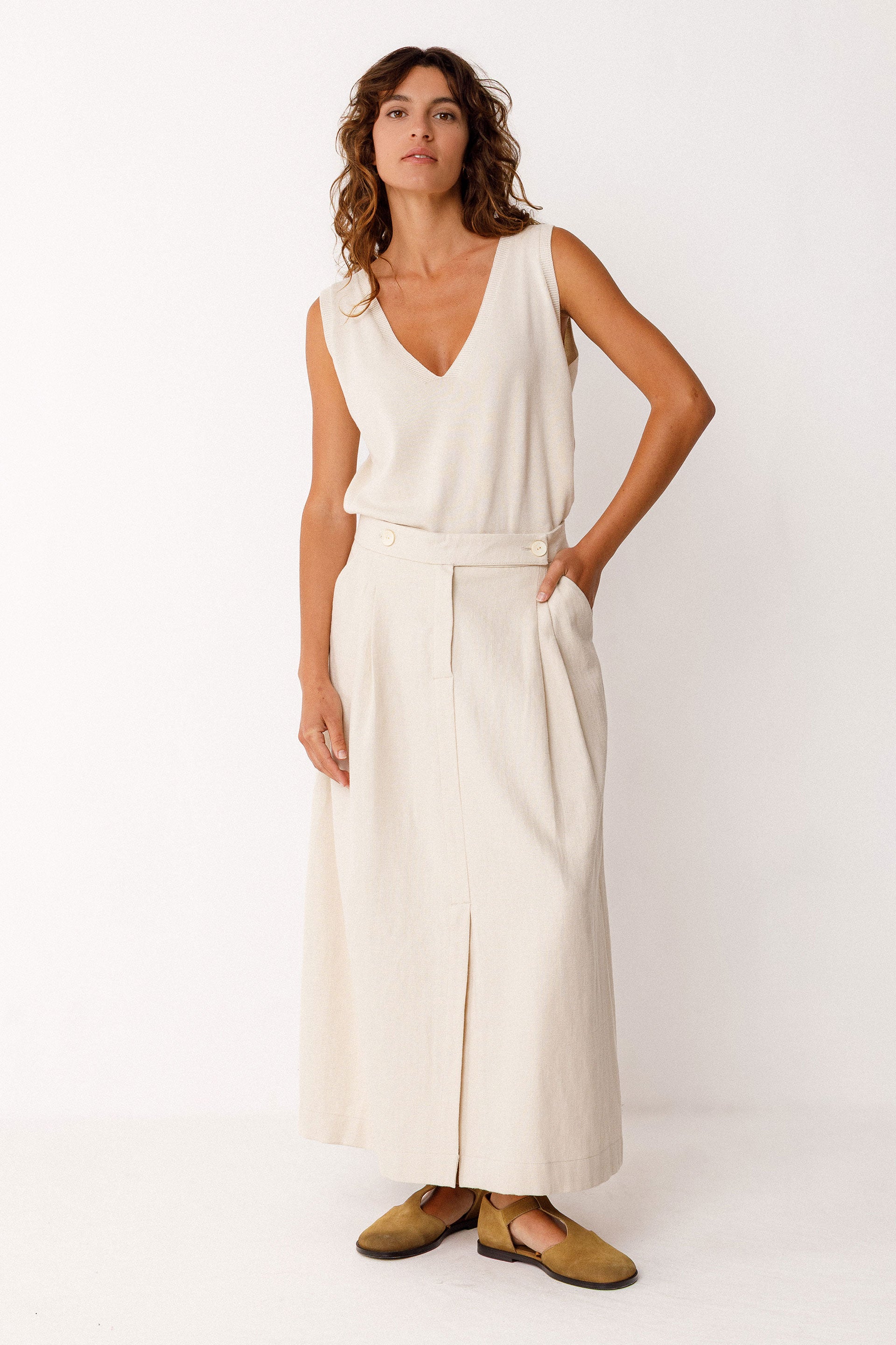 Woman wearing an ivory sleeveless top and ivory organic cotton skirt on a white background