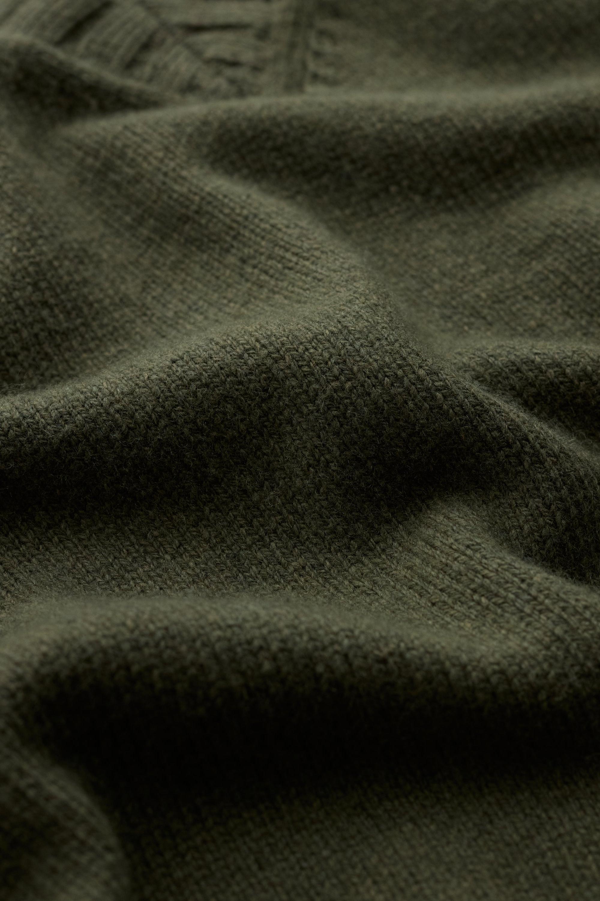 Close up shot of soft khaki knit vest fabric with visible wool texture