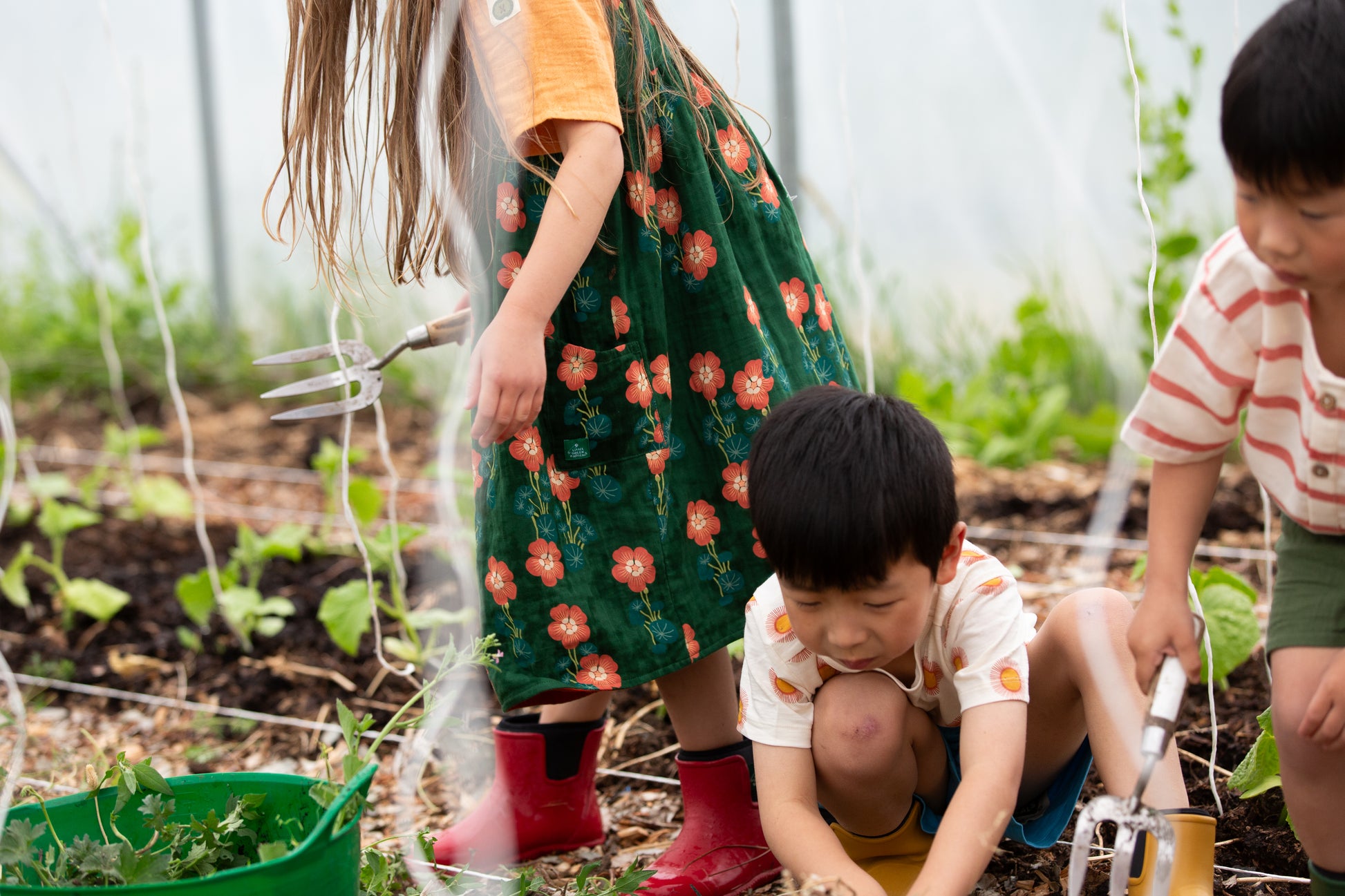 Children gardening in a community garden with tools and plants.