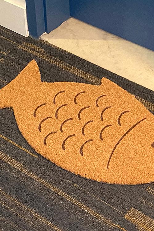 Fish-shaped doormat on a carpeted floor