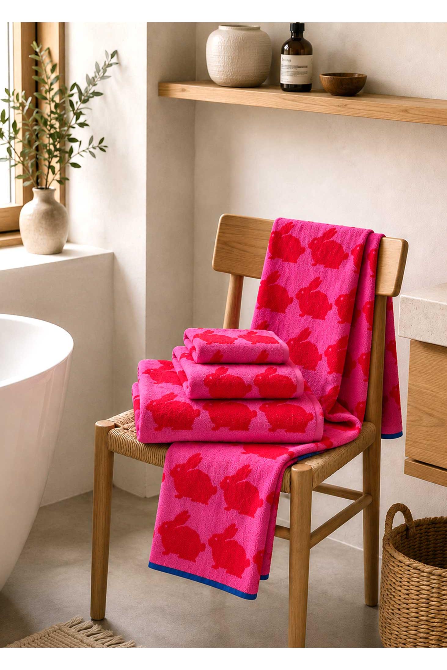 Pink patterned towels on a wooden chair in a bathroom setting