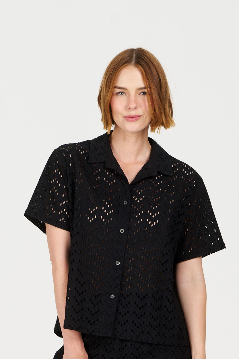 Woman wearing a black broderie shirt against a white background