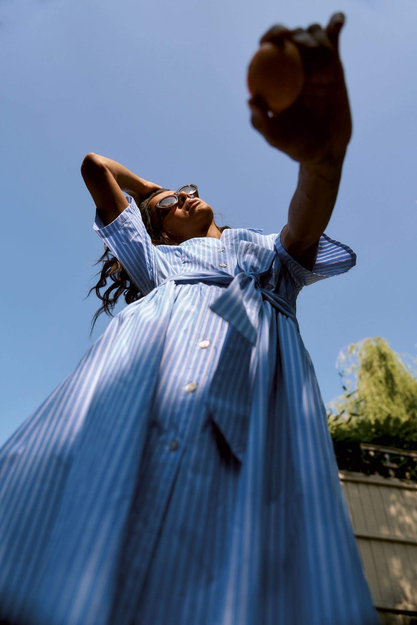 Woman in a blue organic cotton dress against a clear blue sky