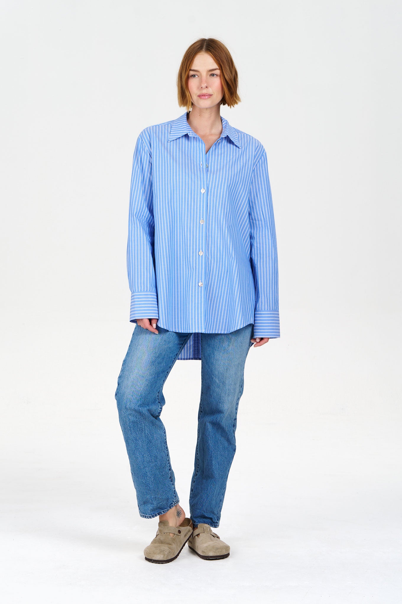 Model wearing a blue striped organic cotton shirt and jeans on a white background