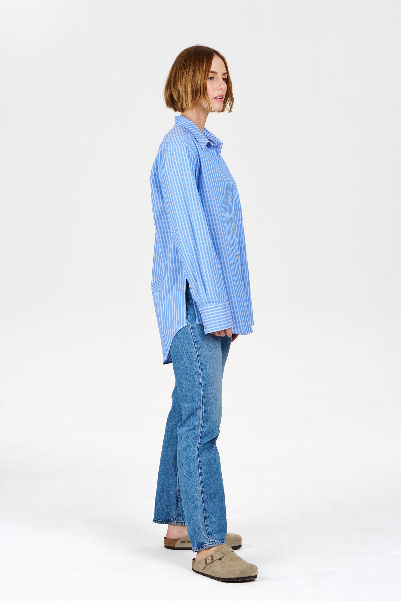 Woman wearing a striped organic cotton shirt and jeans on a white background
