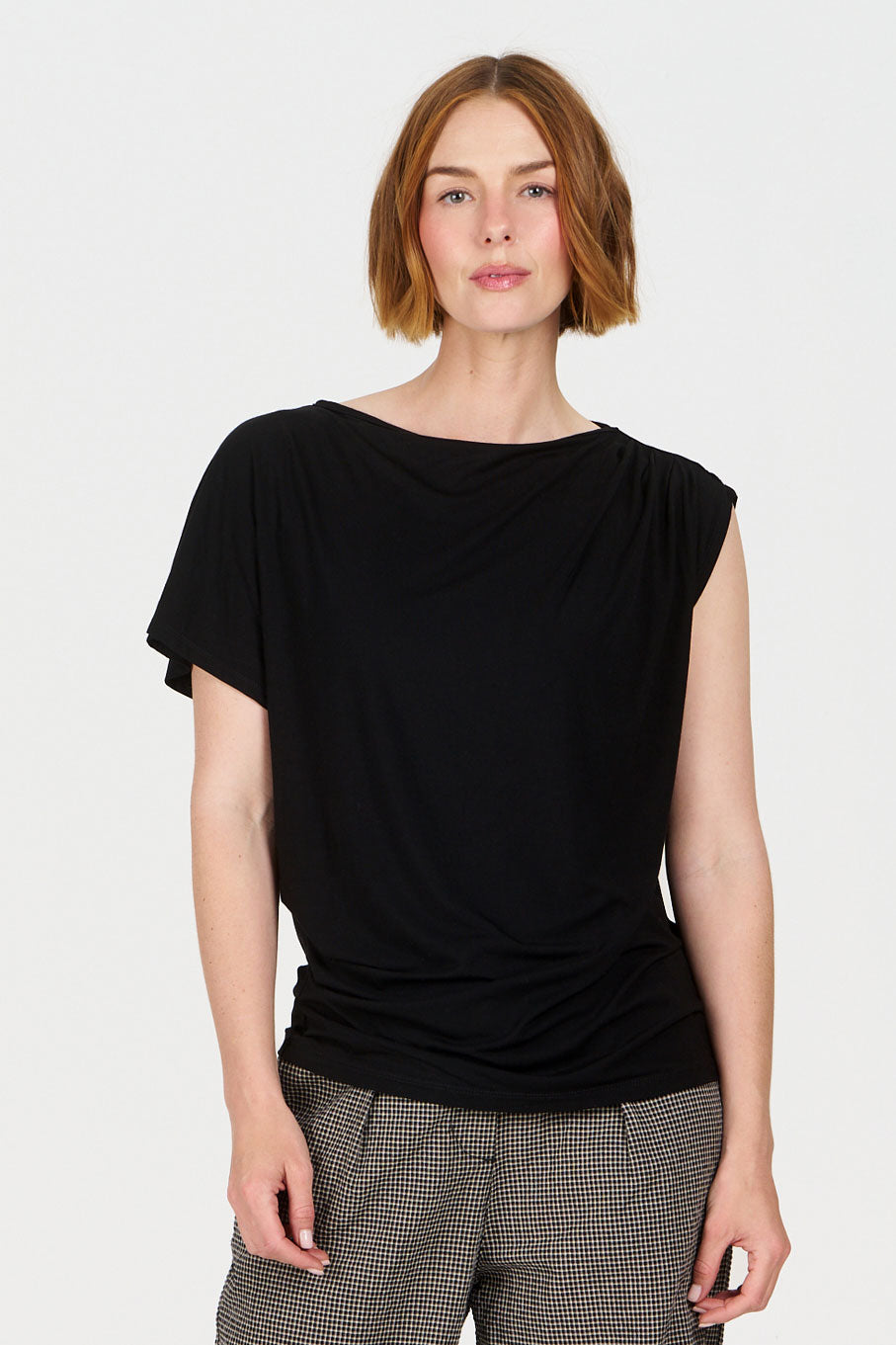 Woman wearing a black top and checkered pants on a white background