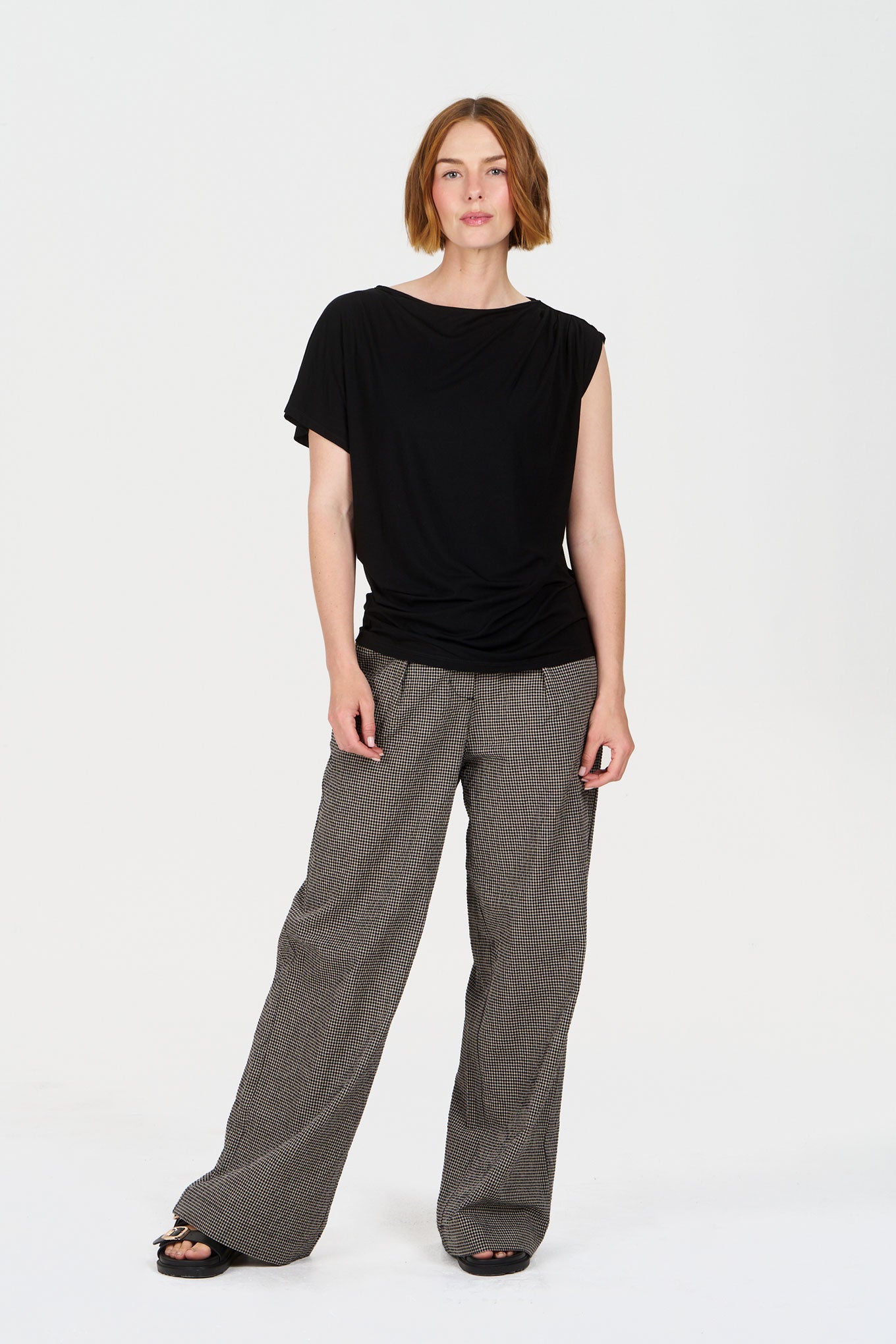 Woman wearing a Komodo black modal top and checkered pants on a white background