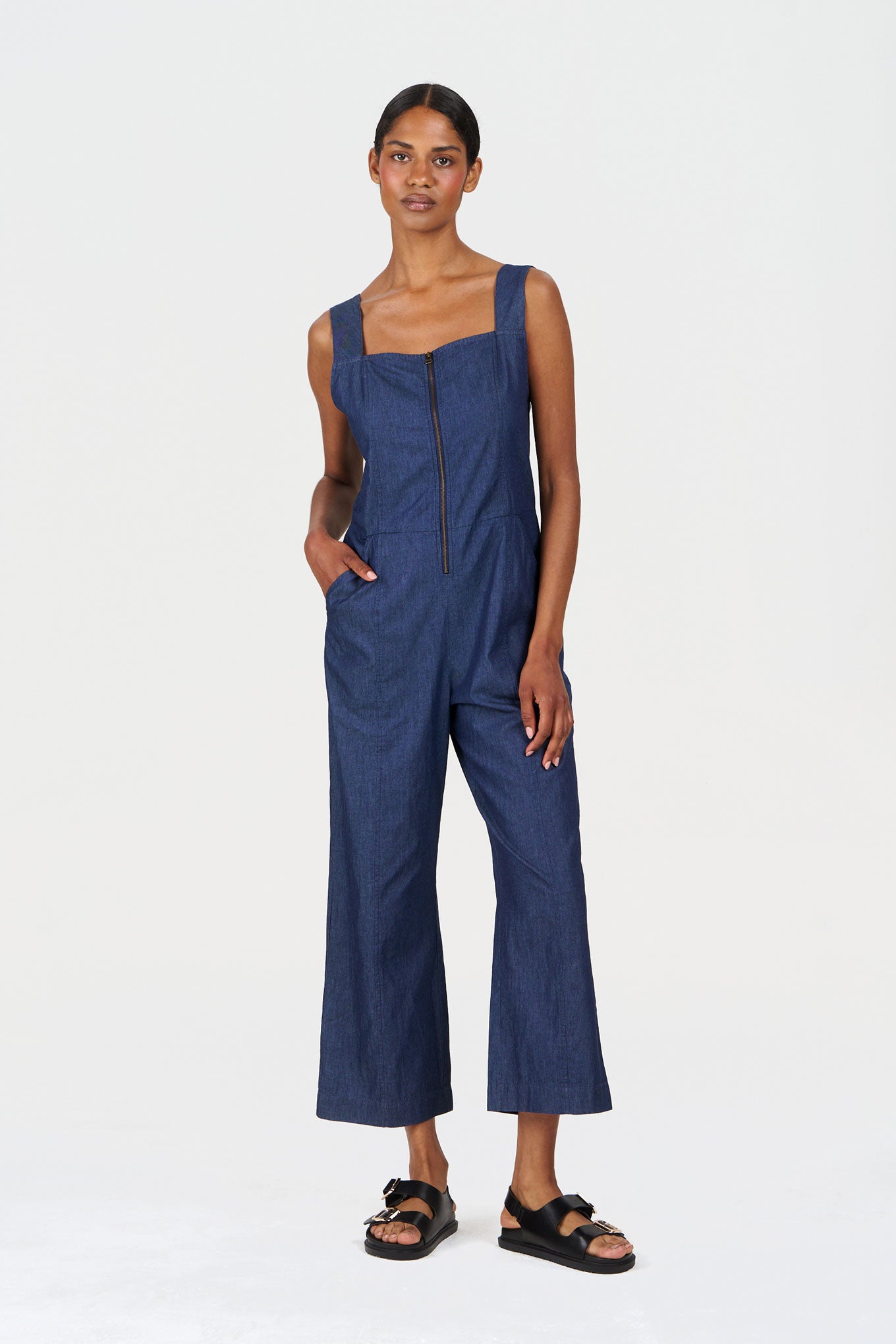 Woman wearing a blue organic cotton jumpsuit on a white background
