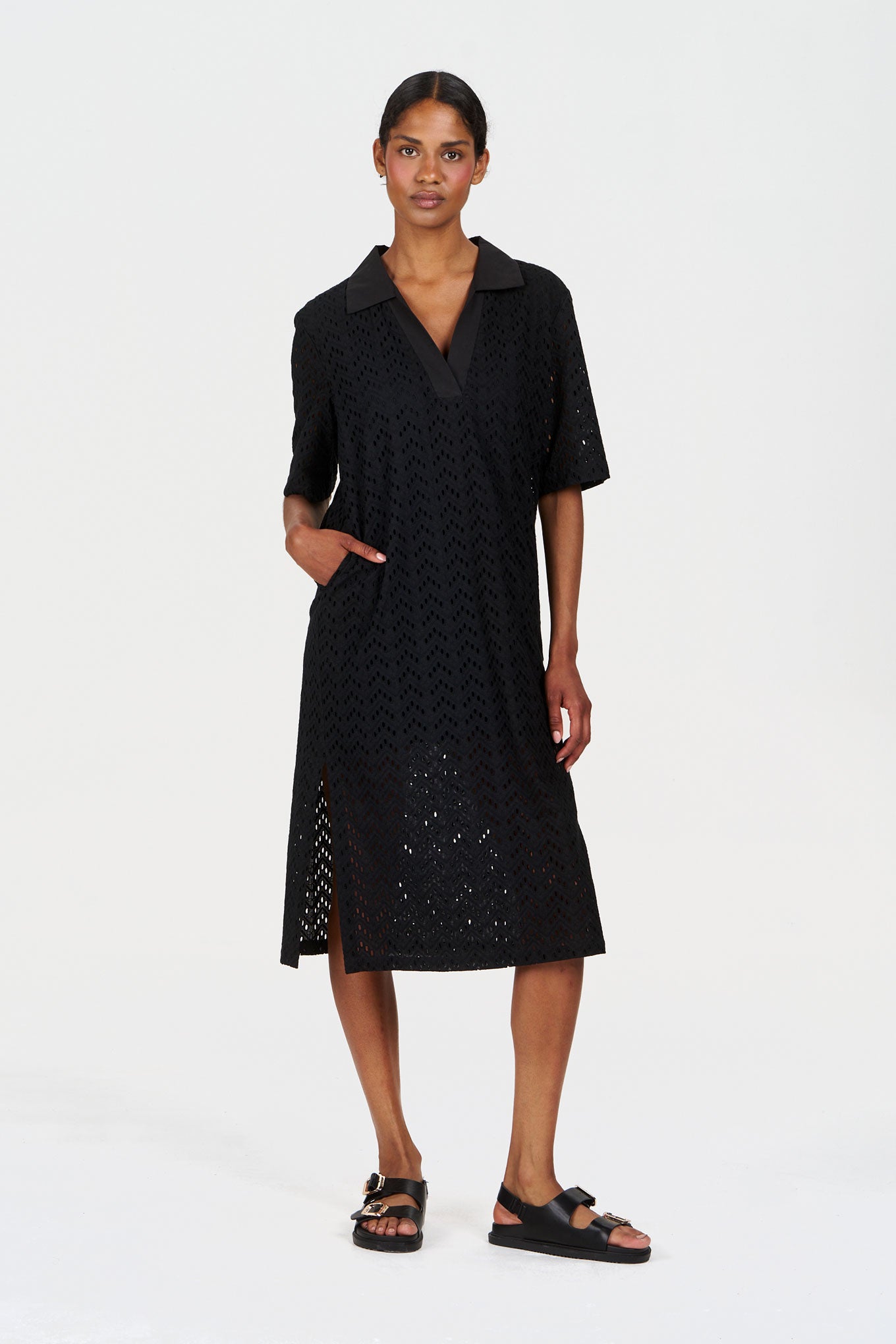 Woman wearing a black broderie organic cotton dress with a white background