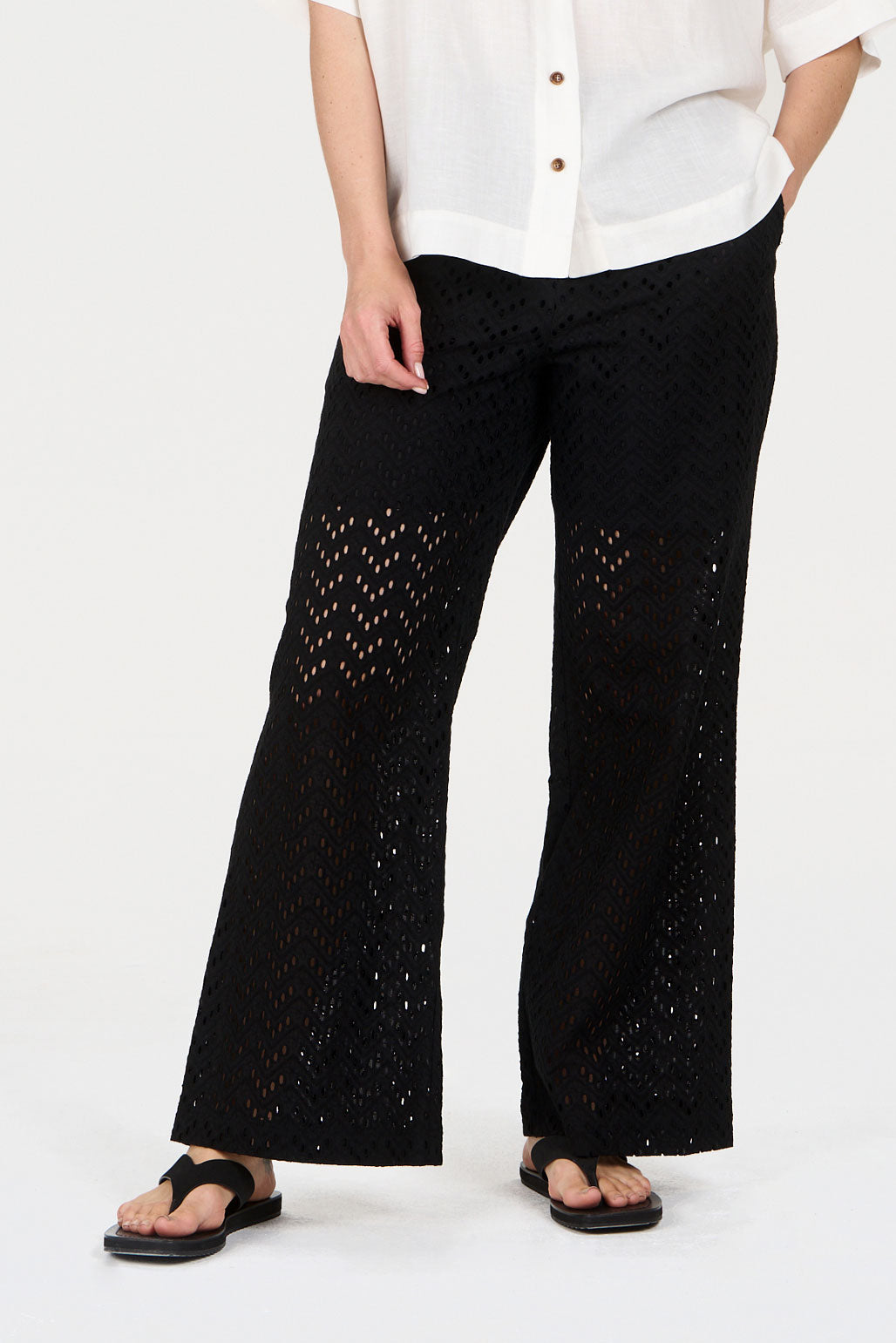 Person wearing black pants with cut-out patterns on a white background