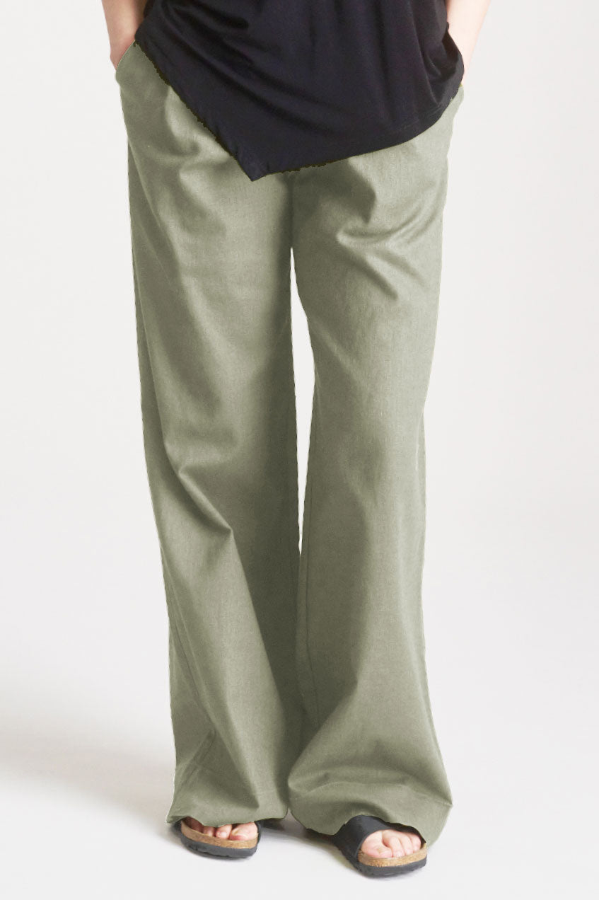 Person wearing olive green wide-leg organic cotton pants and a black top on a white background