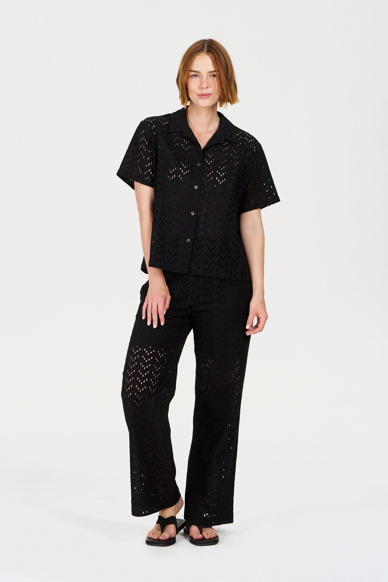Woman wearing a black outfit with intricate patterns on a white background