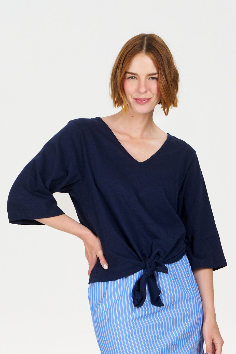 Woman wearing a navy blue top with a tie detail on a white background
