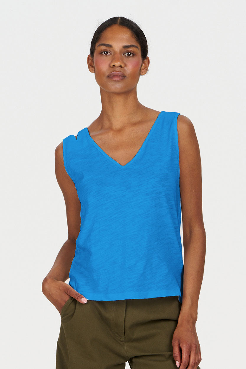 Woman wearing a blue sleeveless top against a white background