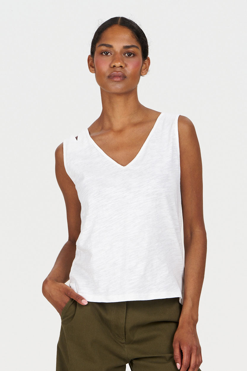Woman wearing a white sleeveless top and green pants on a white background
