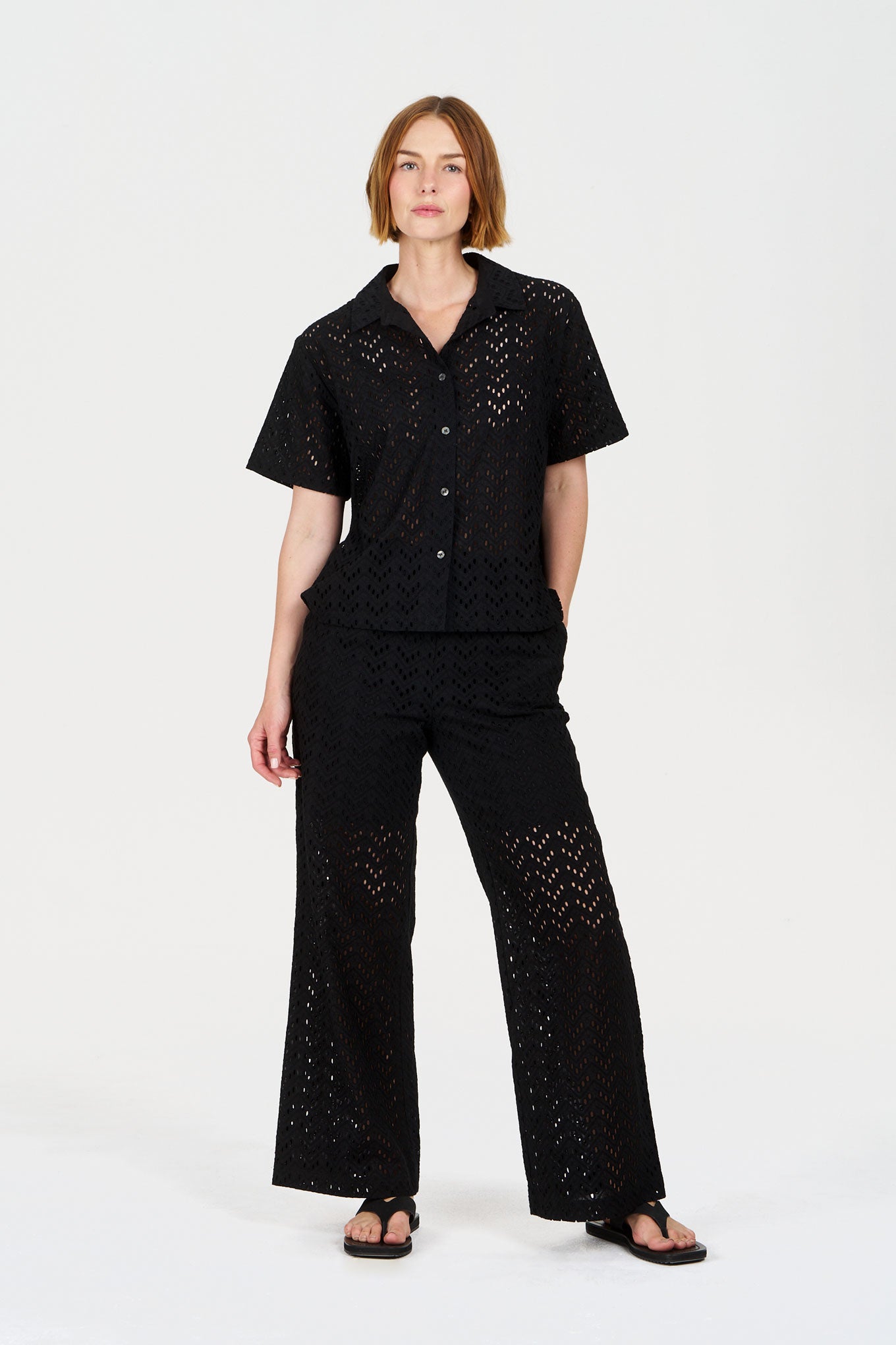 Person wearing a black organic cotton outfit with broderie details on a white background