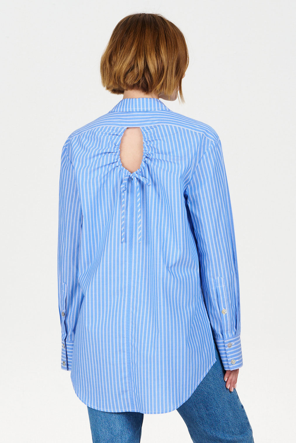 Blue striped shirt with open back worn by a person on a white background