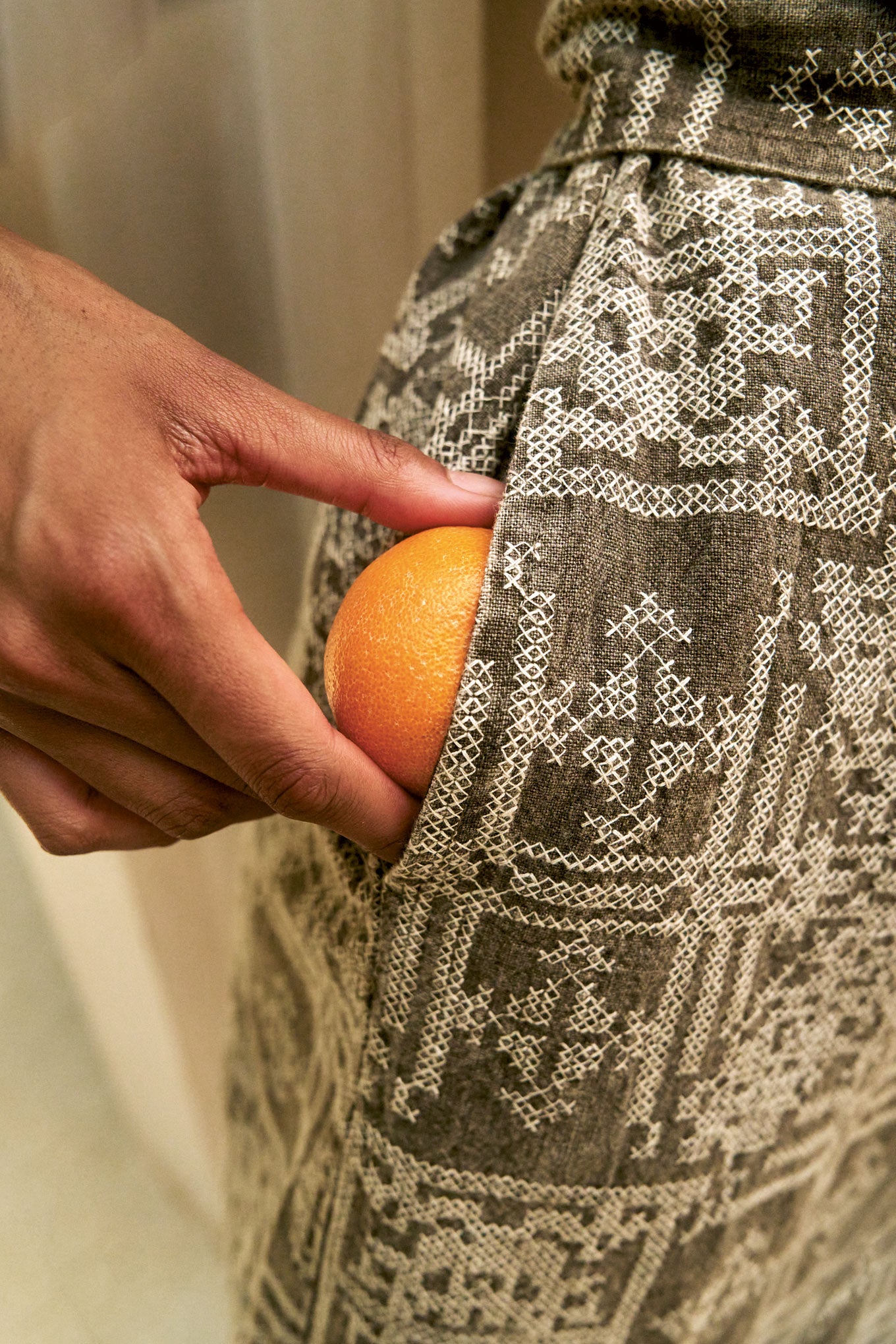 Person putting an orange in pocket of organic cotton linen dress