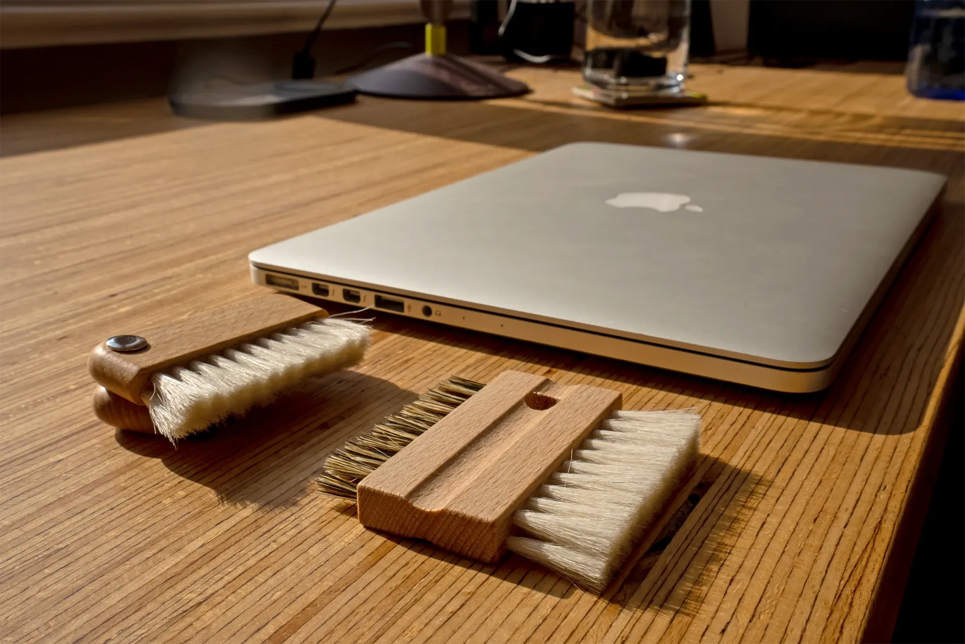 Laptop on a wooden desk with cleaning brushes in front