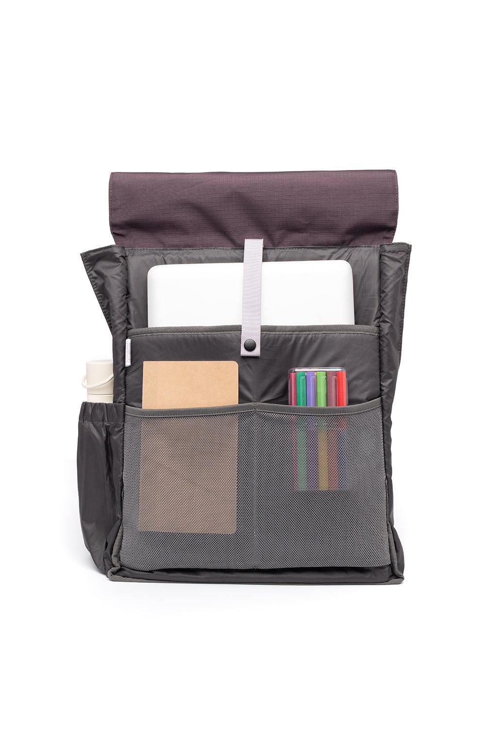 A dark gray nylon laptop sleeve organizer shown open, containing a white laptop, a notebook, a water bottle, and a set of colorful pens, on a solid white background.