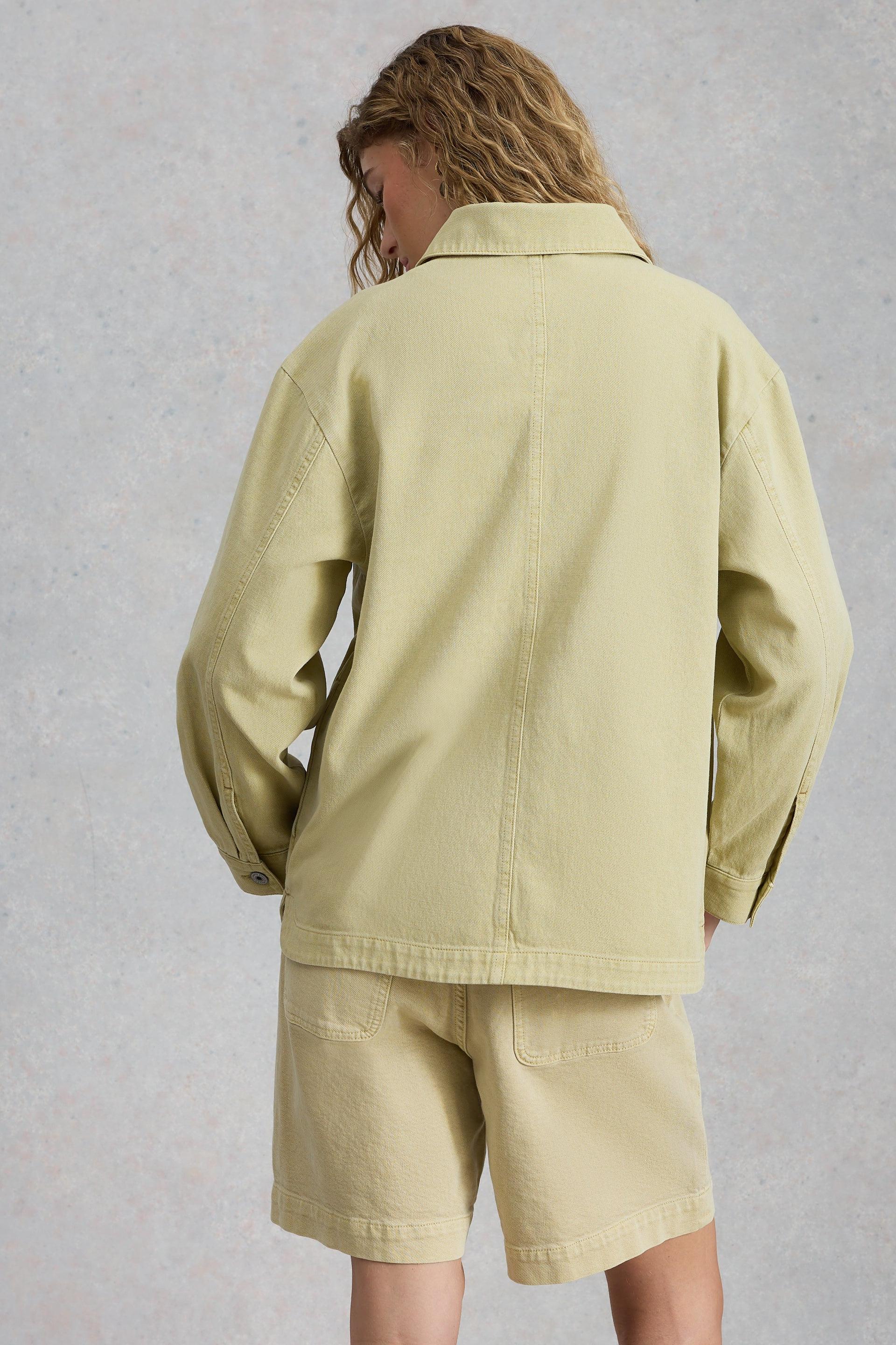 Person wearing a light green jacket and shorts set against a gray background