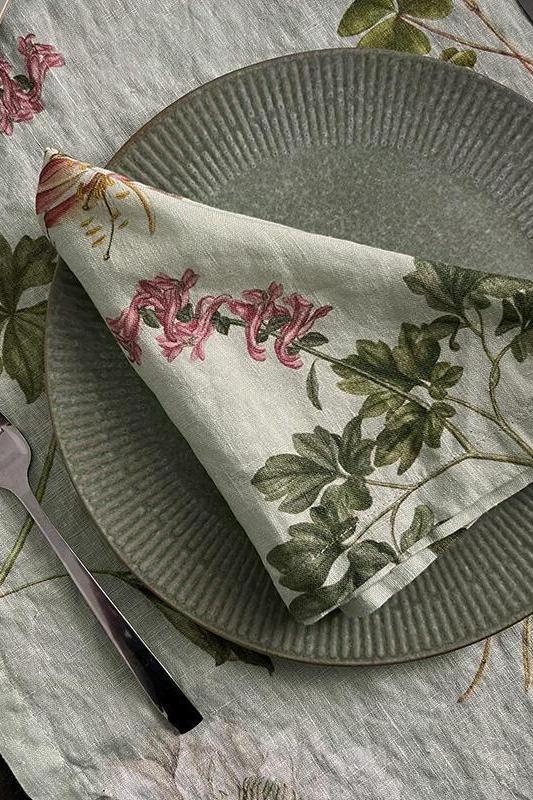 Linen napkin with floral design on a table setting with plates and cutlery.