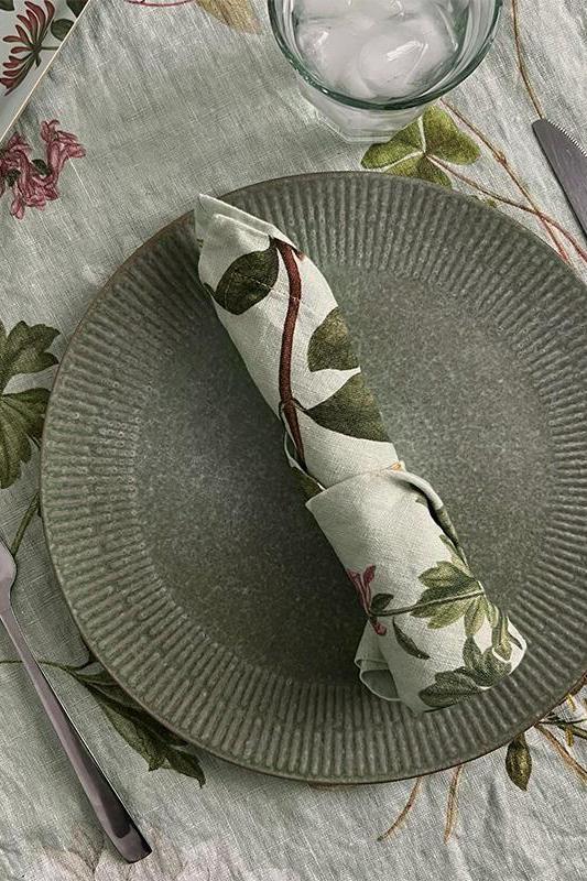 Green ceramic plate with a floral napkin on a patterned tablecloth.