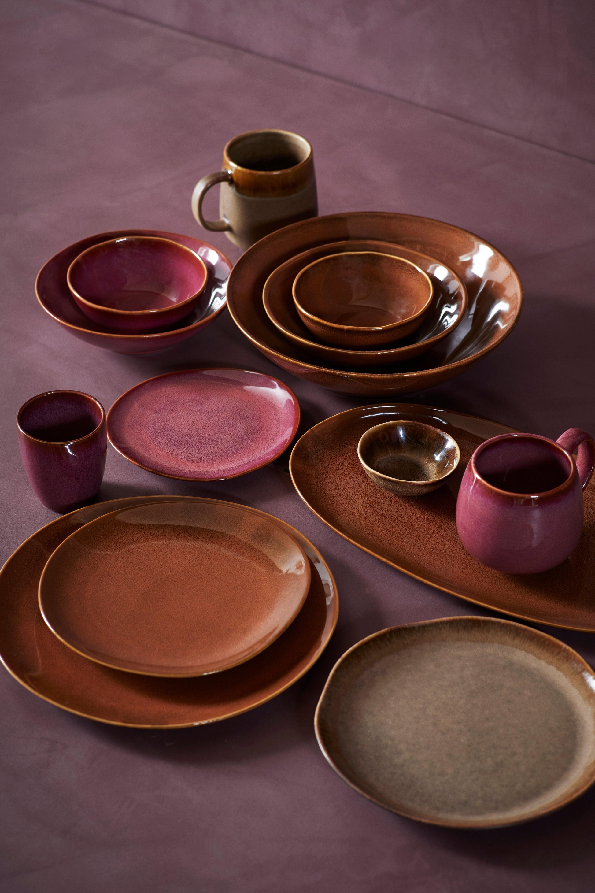 Set of ceramic plates and mugs on a purple surface