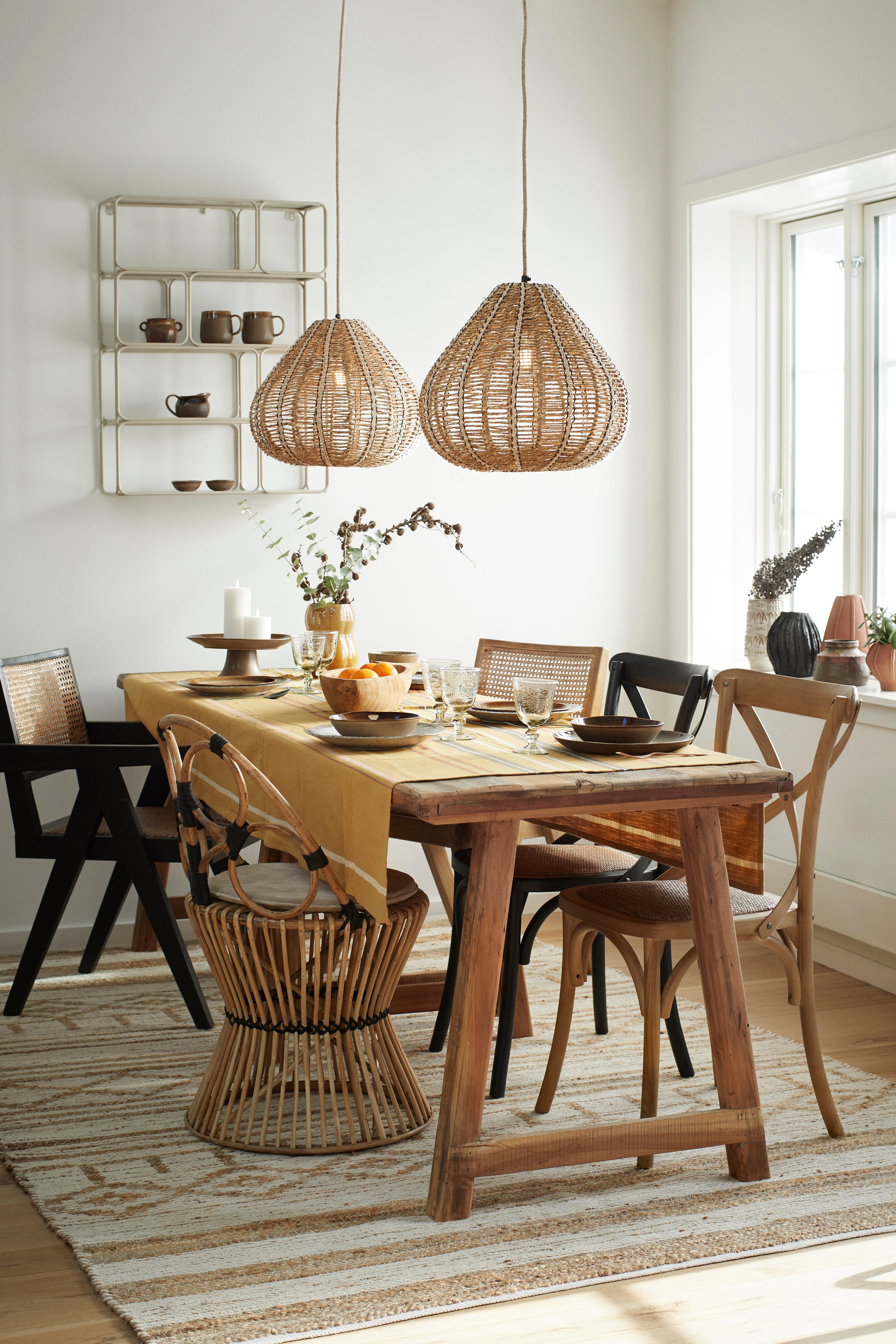 Dining room with wooden table, chairs, and pendant lights in a bright room.