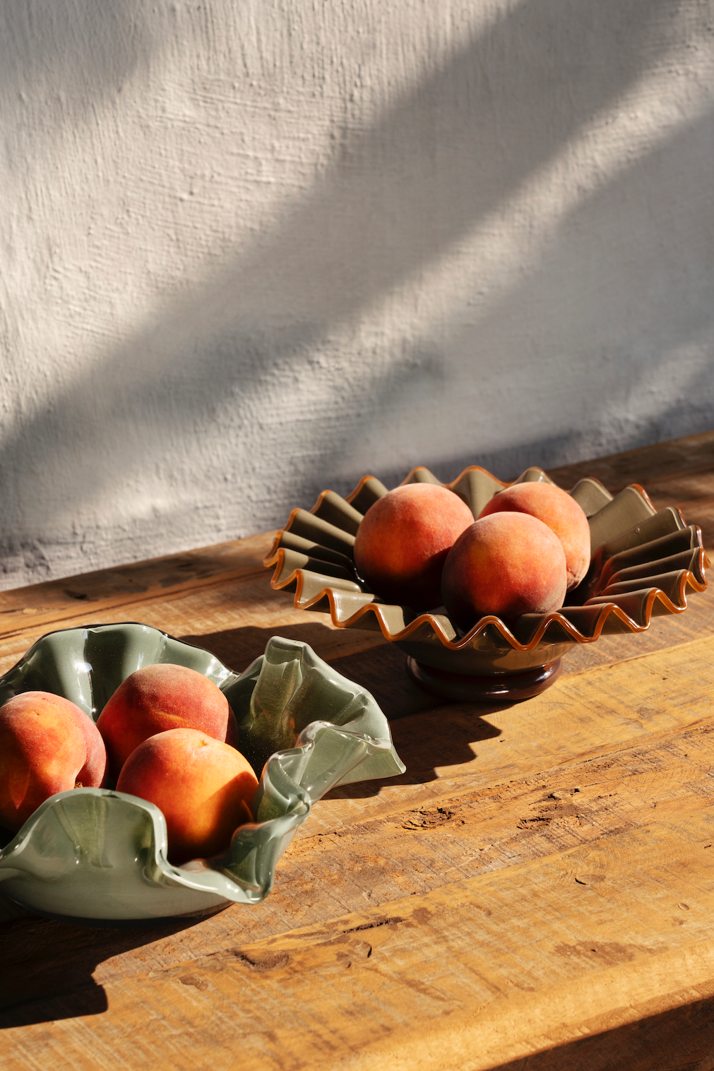 Peaches in ceramic containers on a wooden surface with a textured wall background